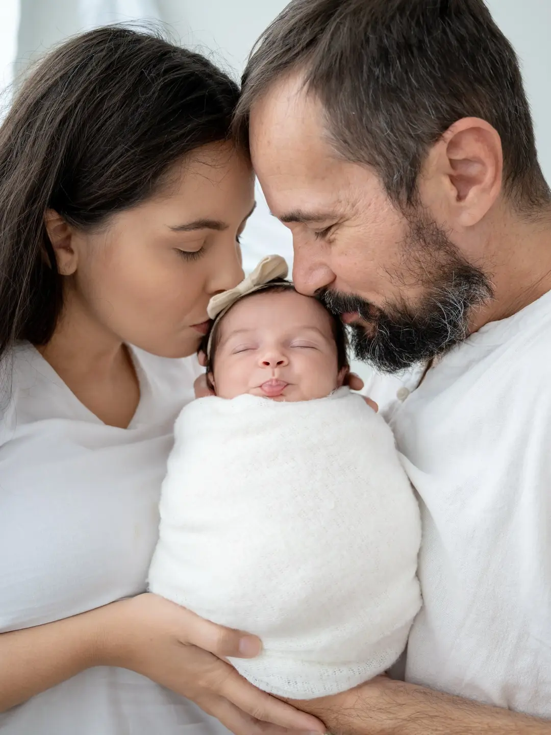 Bebê nos braços dos pais, valorizando mãos, afeto, escala e conexão.